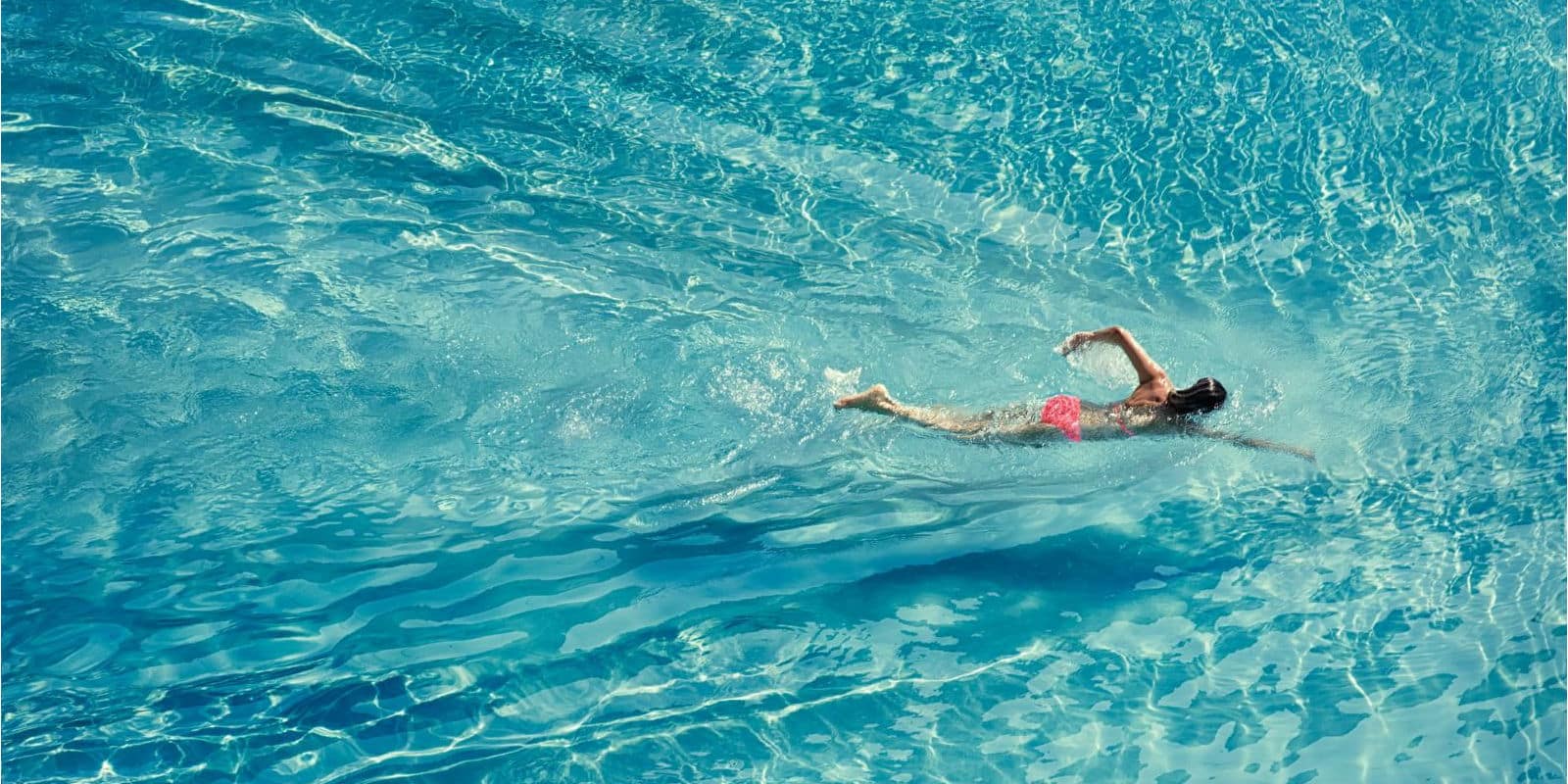 Adult swimmer female swimming front crawl in the sea